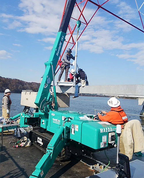 Mini grúa araña MC305 MAEDA elevando a una barcaza para las torres de la TVA en Tennessee.