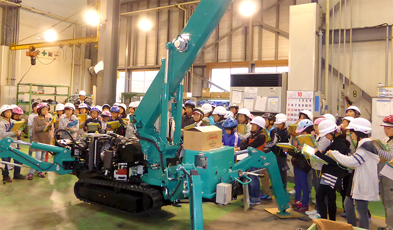 Mini grúa araña MAEDA y niños de primaria en la empresa MAEDA en Japón 